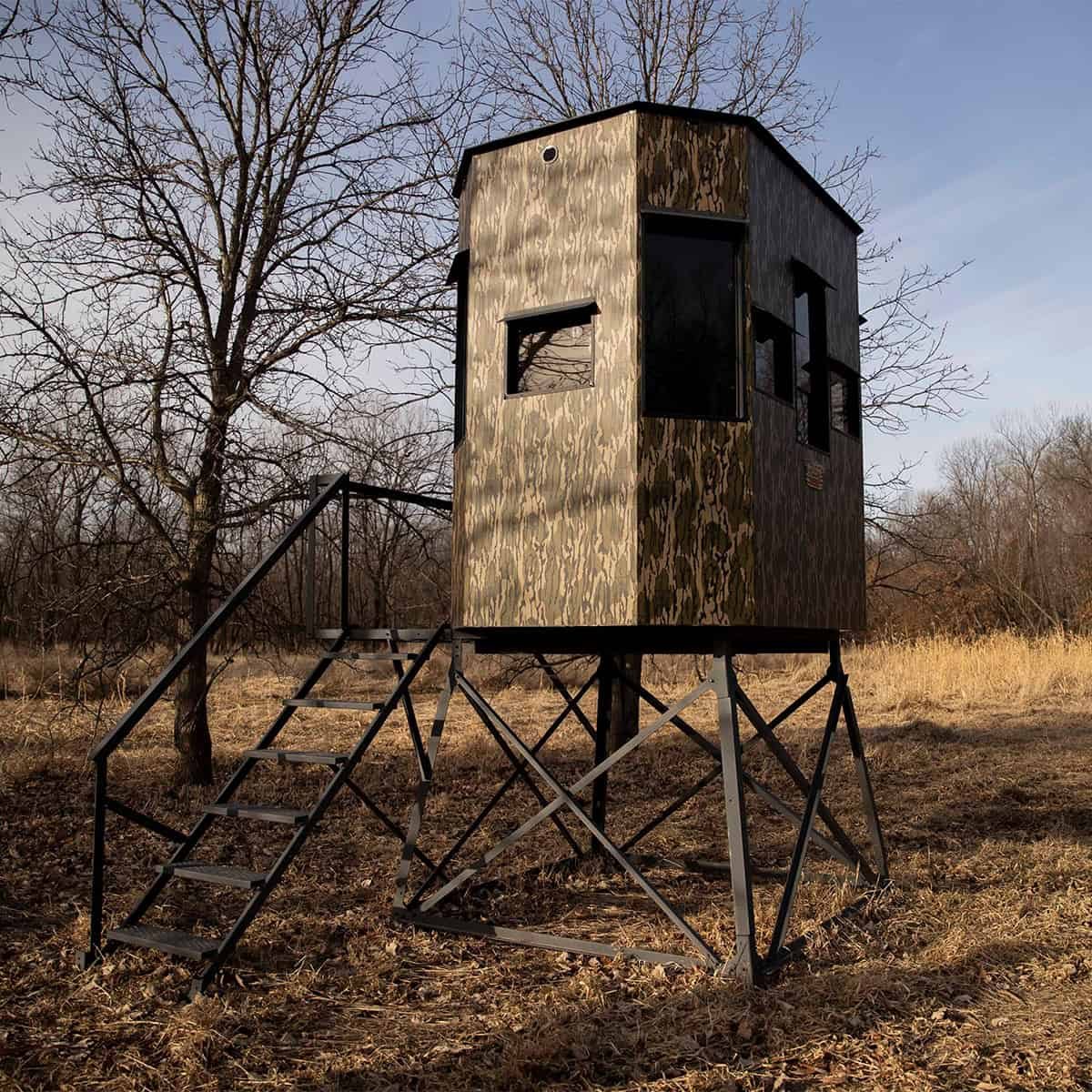 Hunter drawing a bow from a Rutted-Up hunting blind