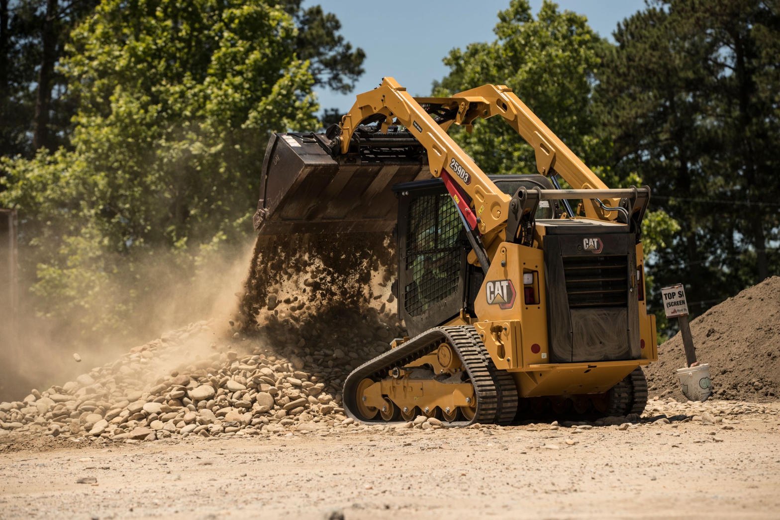 Compact track loader working a gravel driveway in the North Country
